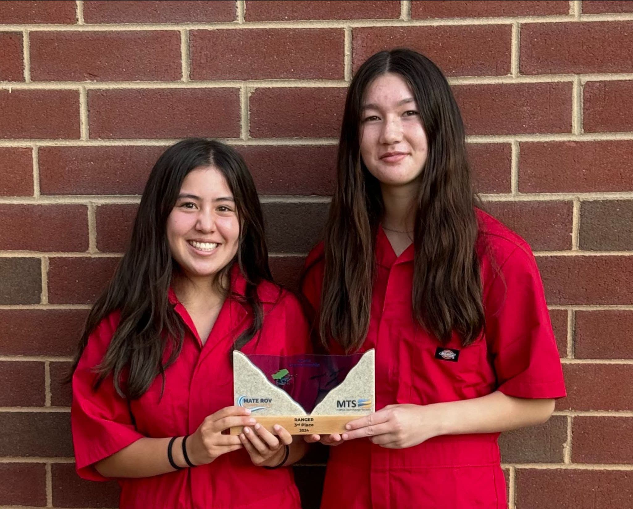 Two Team Members Holding Up the Third Place Award